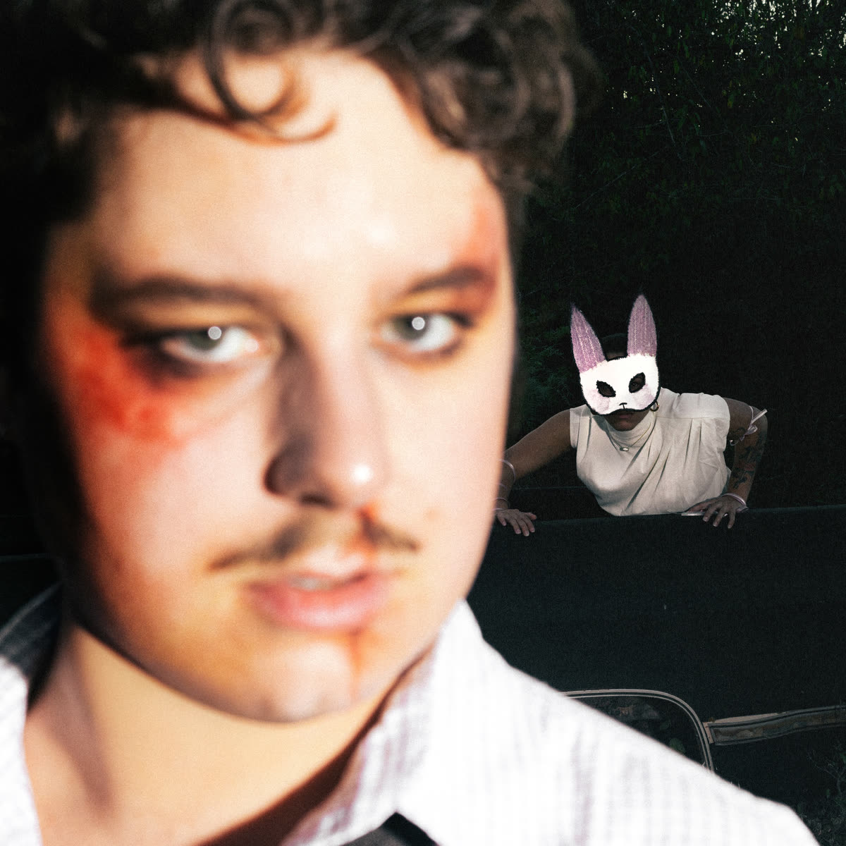 Photograph of the subject with an unidentified masked figure behind him